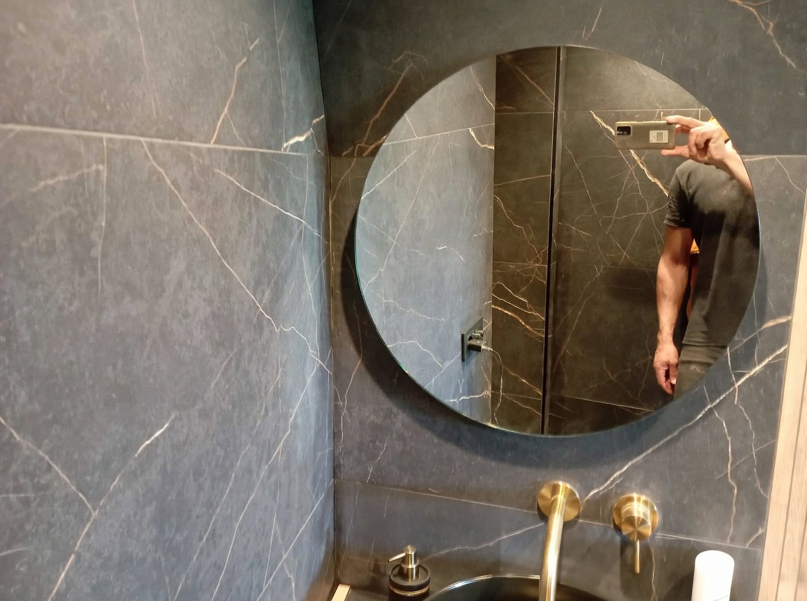 Luxe badkamer in donker marmer met fijne aders en ronde spiegel, door MoreThanTiles