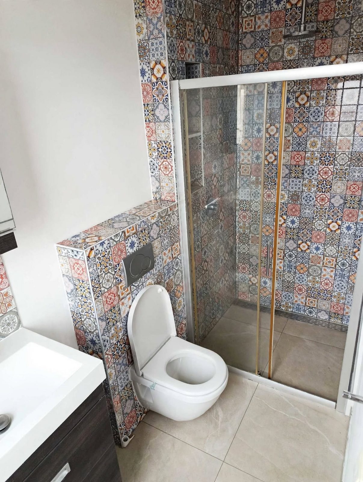 Afgewerkte badkamer met kleurrijke Marokkaans-Portugese tegels, glazen douchewand, hangtoilet en wastafel